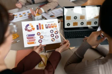 Echipa unei agenții de marketing analizând un infografic în cadrul unei ședințe de proiect