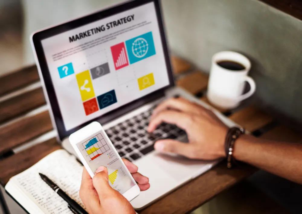 Specialist care lucrează la o strategie de marketing online pe laptop și telefon